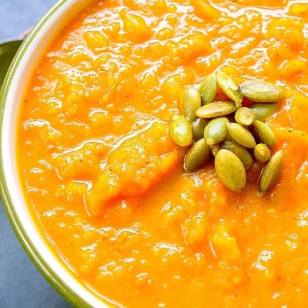 Bowl of dairy-free butternut squash soup topped with green pumpkin seeds.