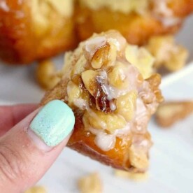Close-up of a hand with light blue nail polish holding a walnut pastry piece, perfect for brunch menu ideas.