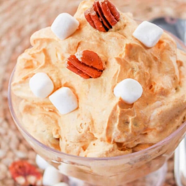Pumpkin cream cheese mousse topped with marshmallows and pecans in a glass dish.