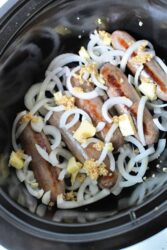Crockpot Brats combined with sliced onions, garlic, and butter create a mouthwatering slow-cooker delight.